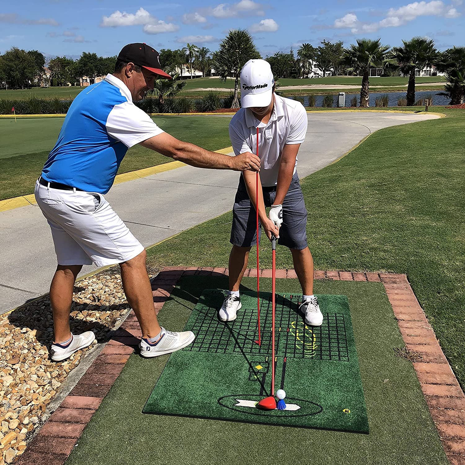 Man showing another person how to practice golf swings on the Golf ForeMat, a golf practice mat.